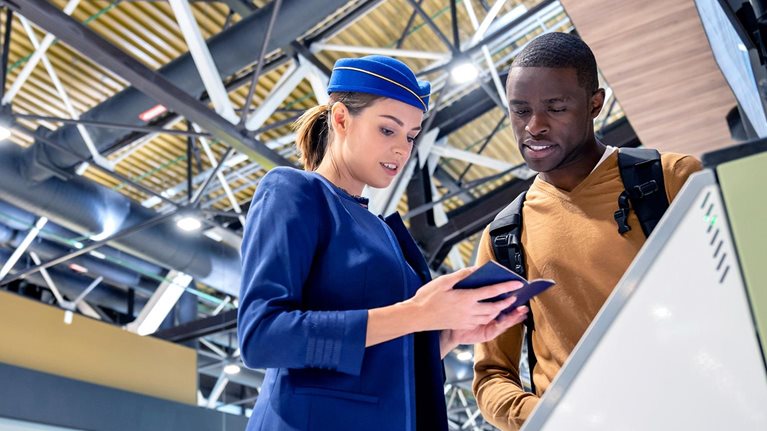 Airline attendant helping a traveler do the self check-in at the airport.