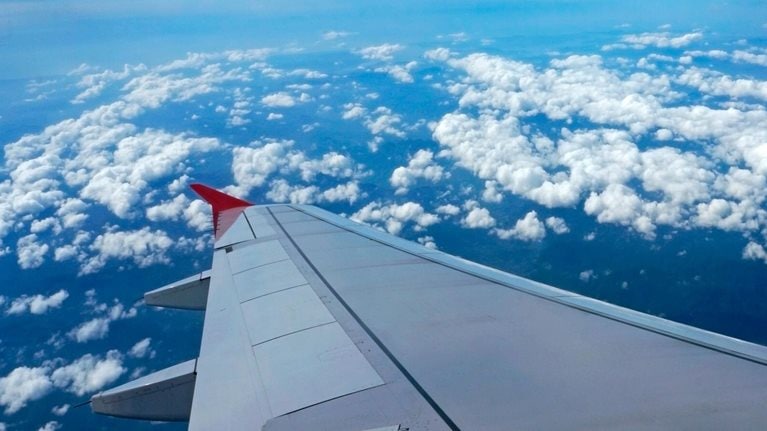 photo view of plane's wing flying over clouds and blue sky
