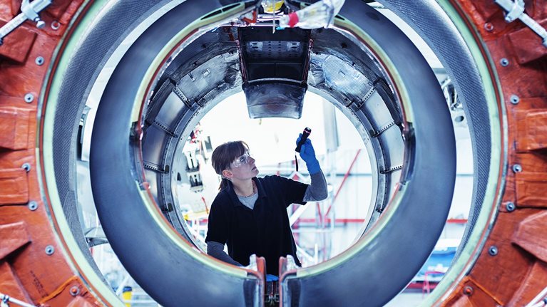 Image of an aircraft maintenance engineer inspecting a jet engine.