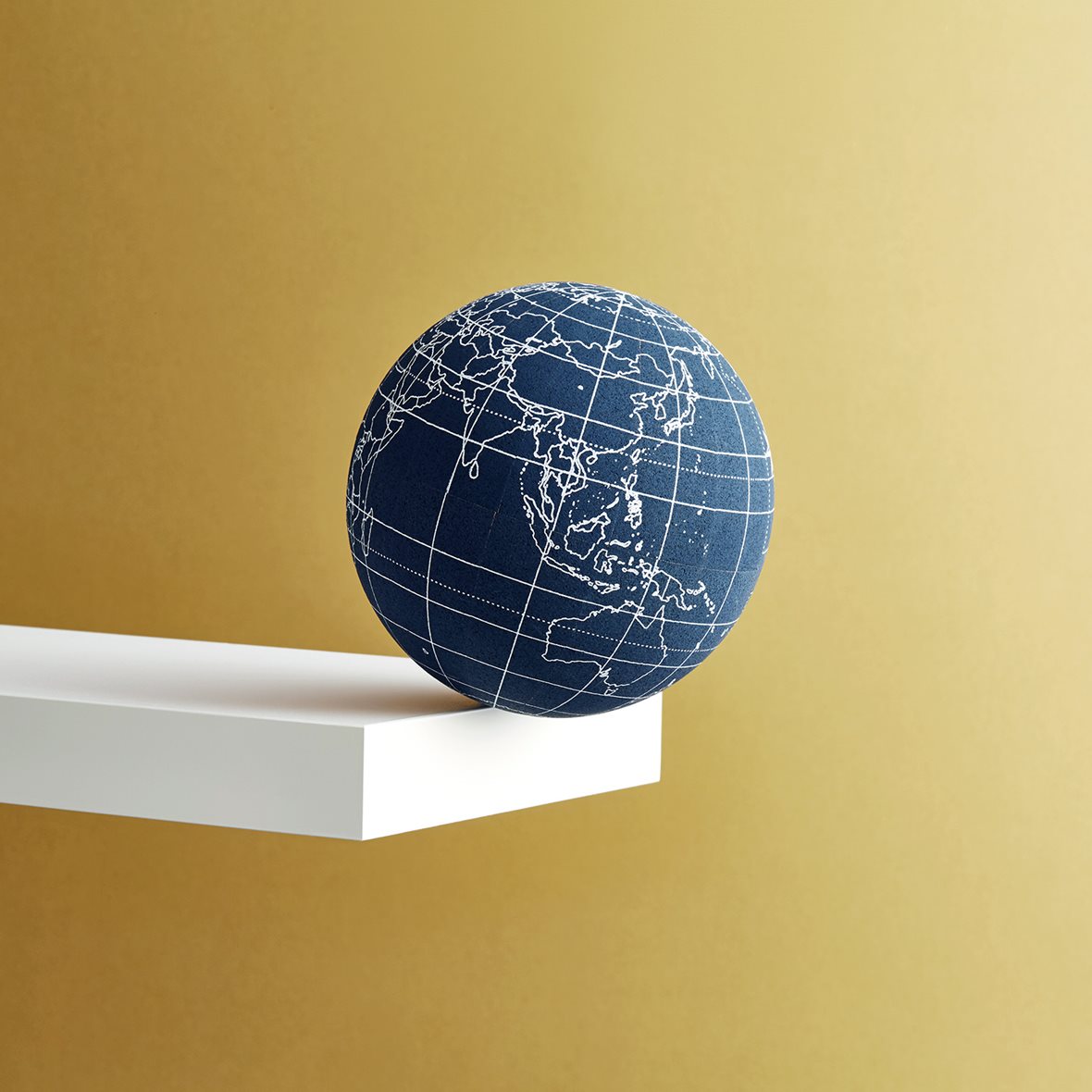 Image of a globe balanced on the edge of a shelf.