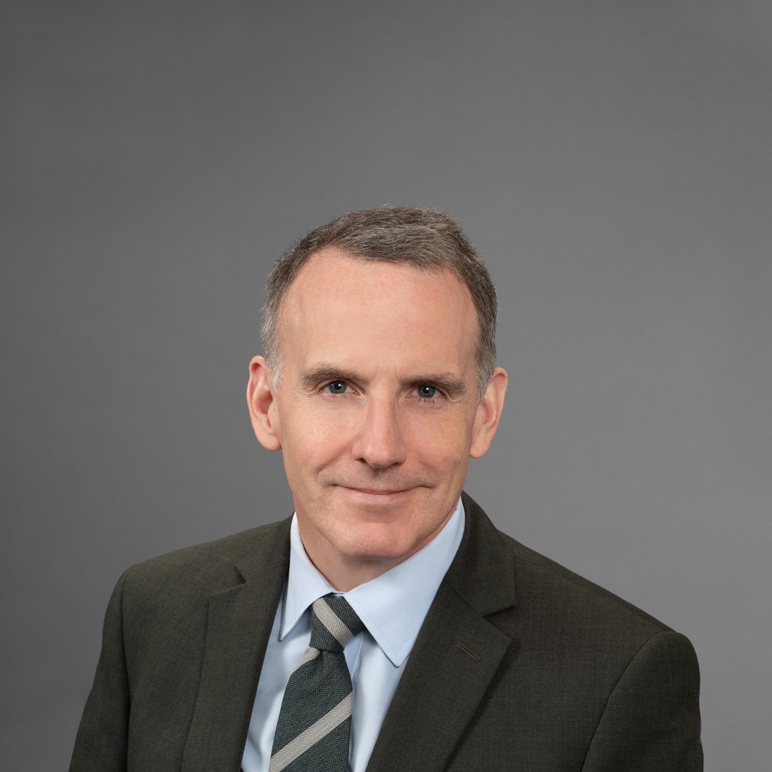 Portrait of Ed Glaeser in a dark gray suit against a seamless gray backdrop.