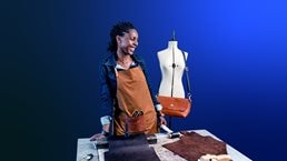 An image of a small business owner sharing a laugh at her design studio, where she makes leather goods to sell in her shop.
