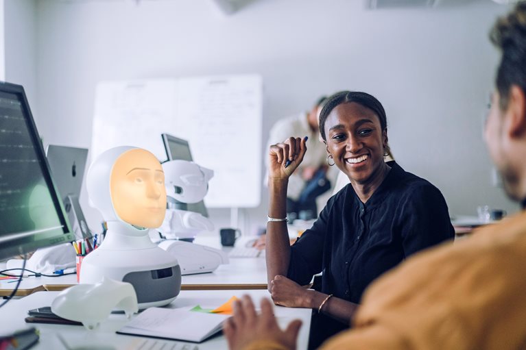 Smiling female PhD student discussing with man at desk in innovation lab - stock photo