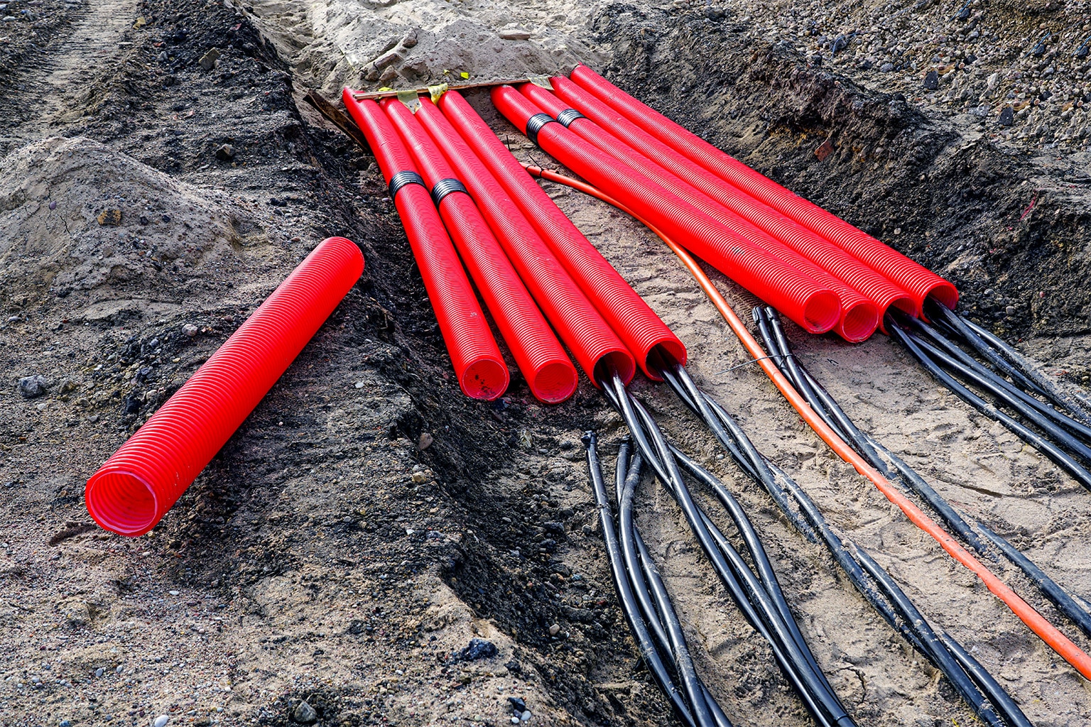 Photograph of powerlines wrapped in red sheathing in a trench.