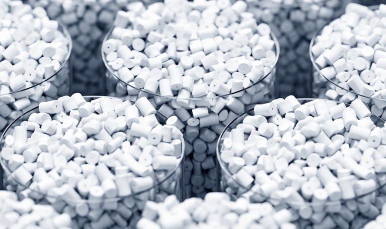 Multiple transparent containers filled with small white cylindrical plastic pellets arranged in a repeating pattern.