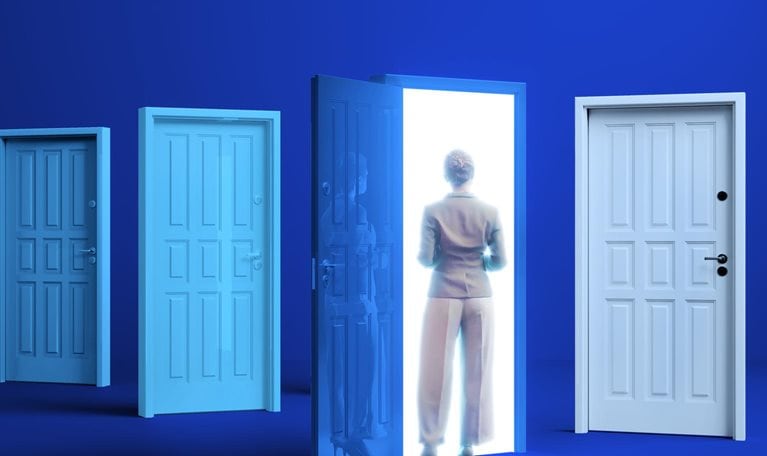 A woman in business attire stands before a brightly lit doorway. Several other closed doors of varying shades of blue are to her left and right.