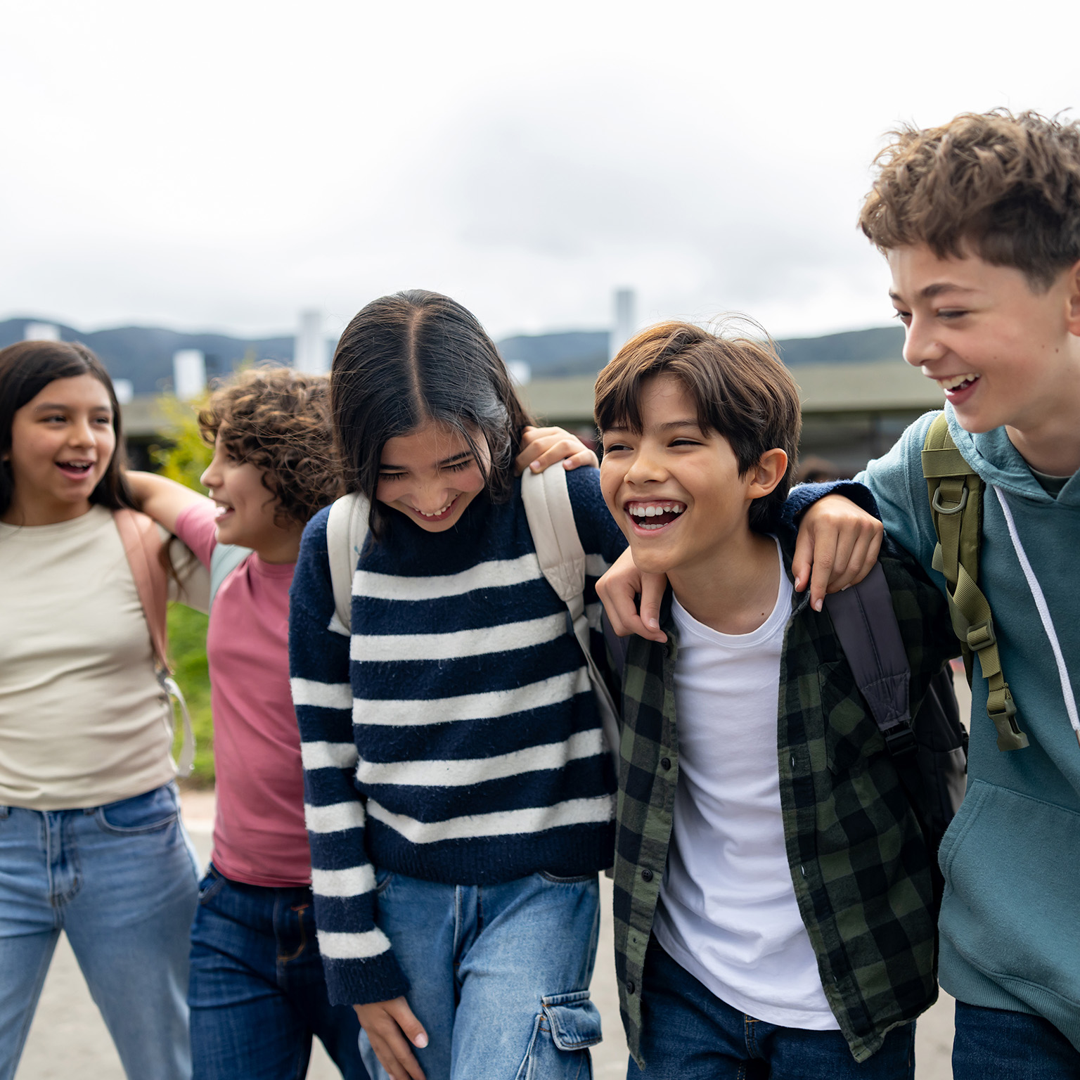 A group of youths smiling, laughing as they walk shoulder to shoulder