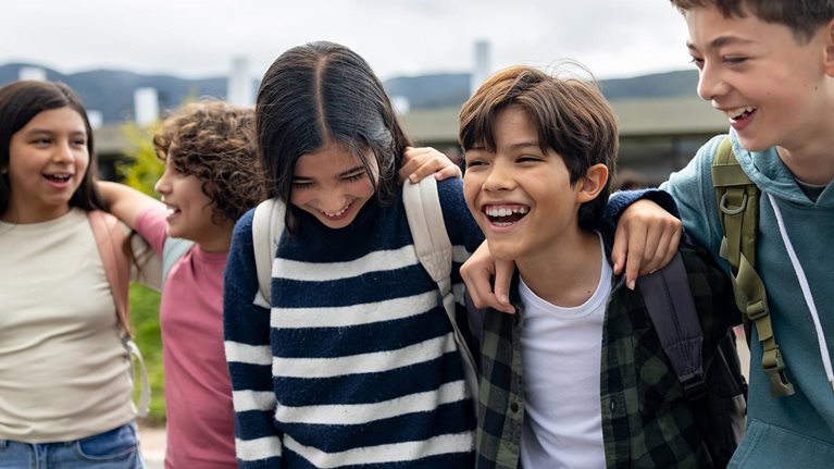 A group of youths smiling, laughing as they walk shoulder to shoulder