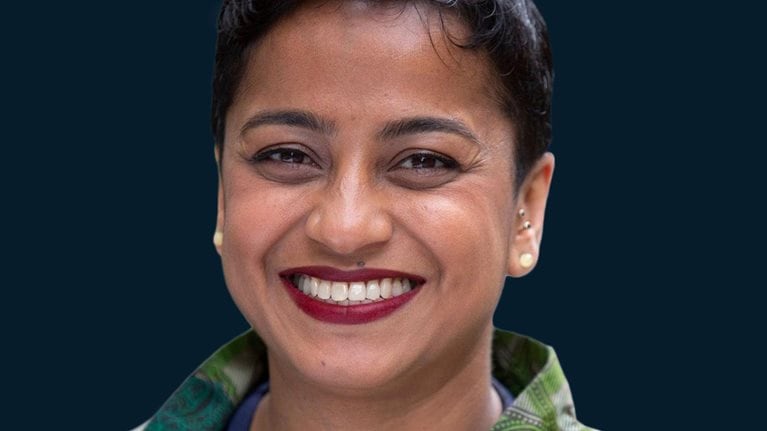 Mental health advocate Poppy Jaman smiles towards the camera.