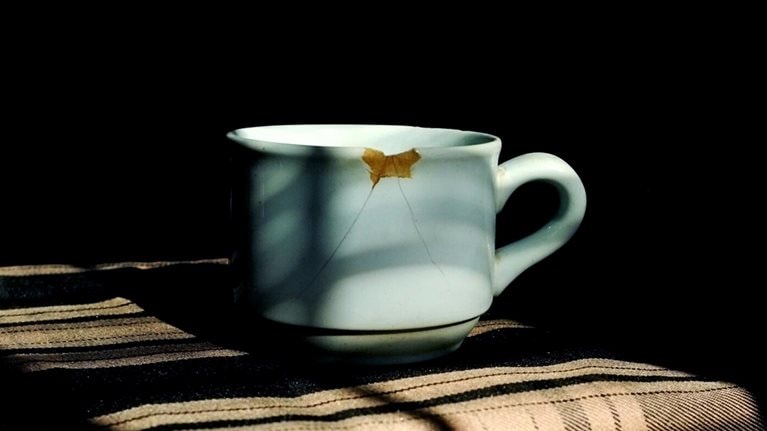 Close-Up Of Broken Coffee Cup Against Black Background