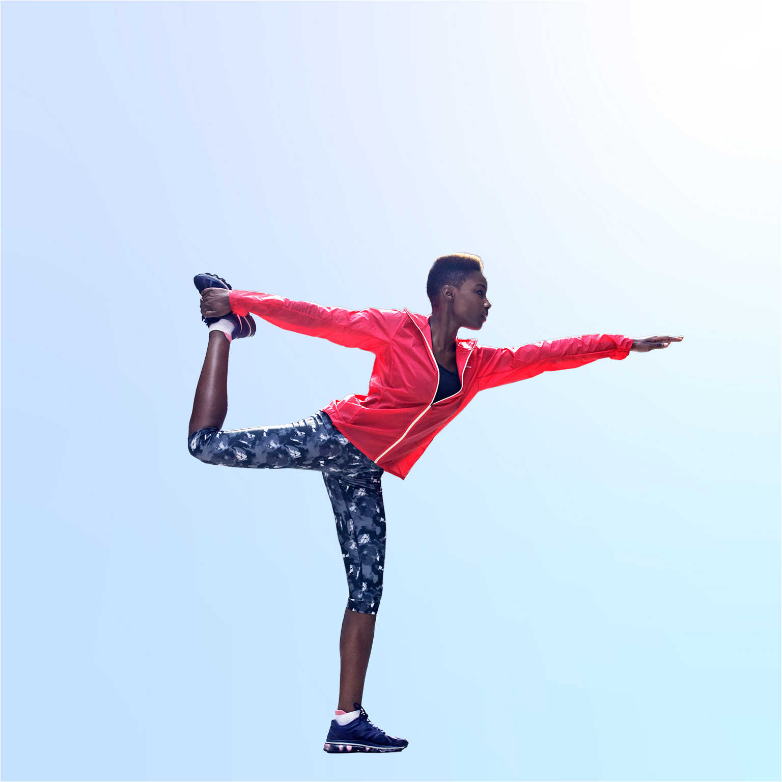 Woman doing yoga in king dancer pose on sidewalk in city