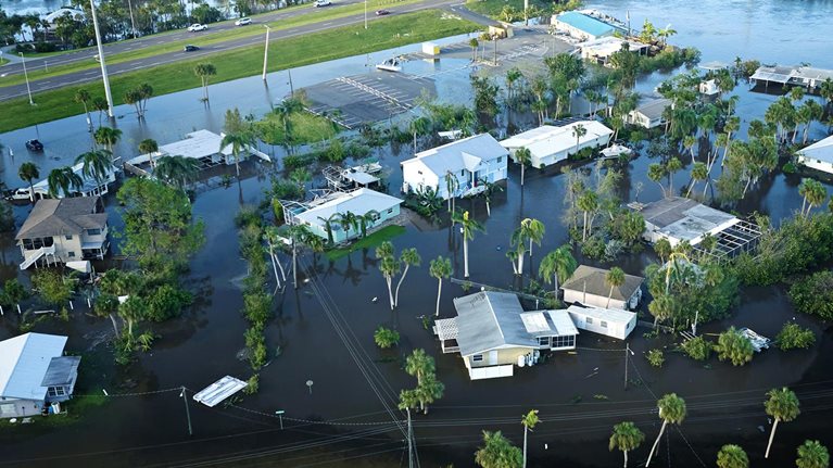 An aerial perspective of a heavily flooded Florida neighborhood next to a river after Hurricane Ian.