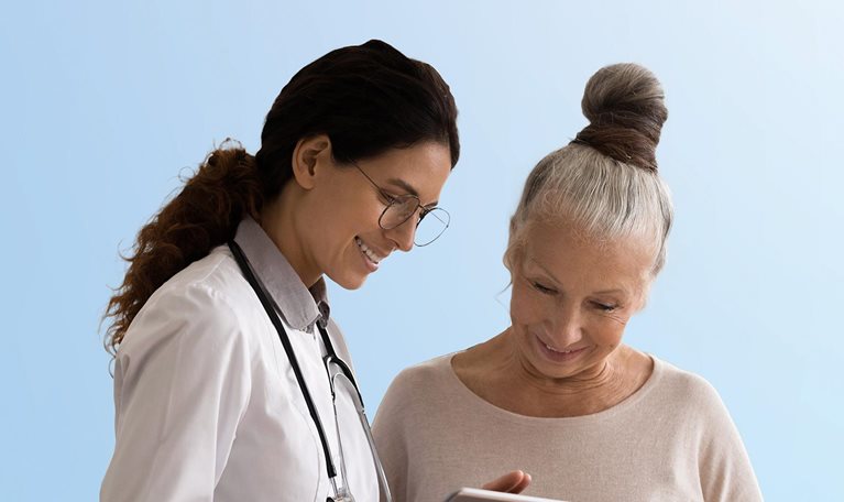 Happy doctor and senior patient use tablet at consultation