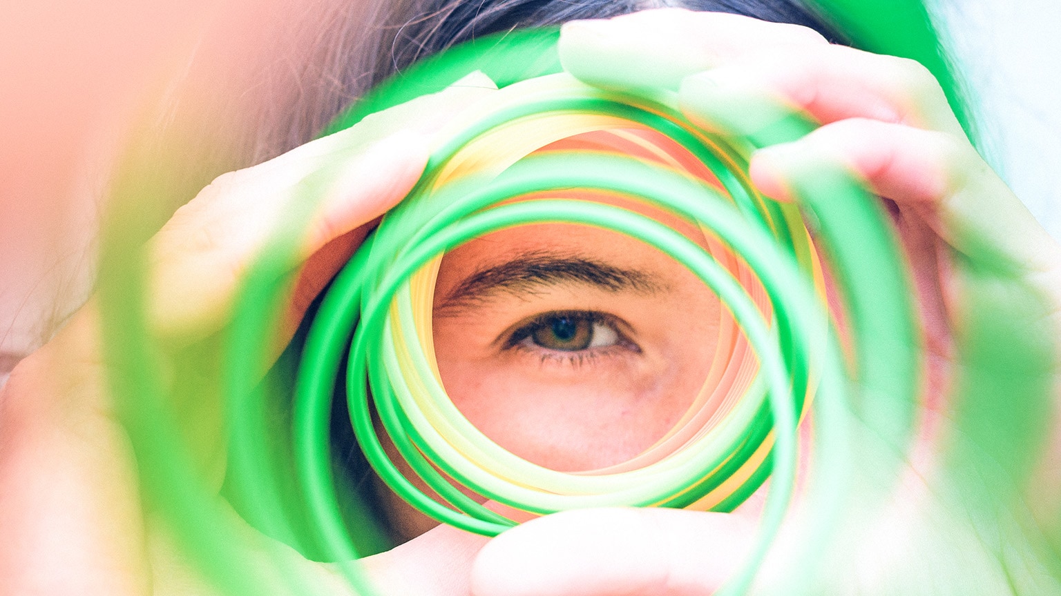 Close-up image of a person looking through a series of circles like its a tube with one eye.