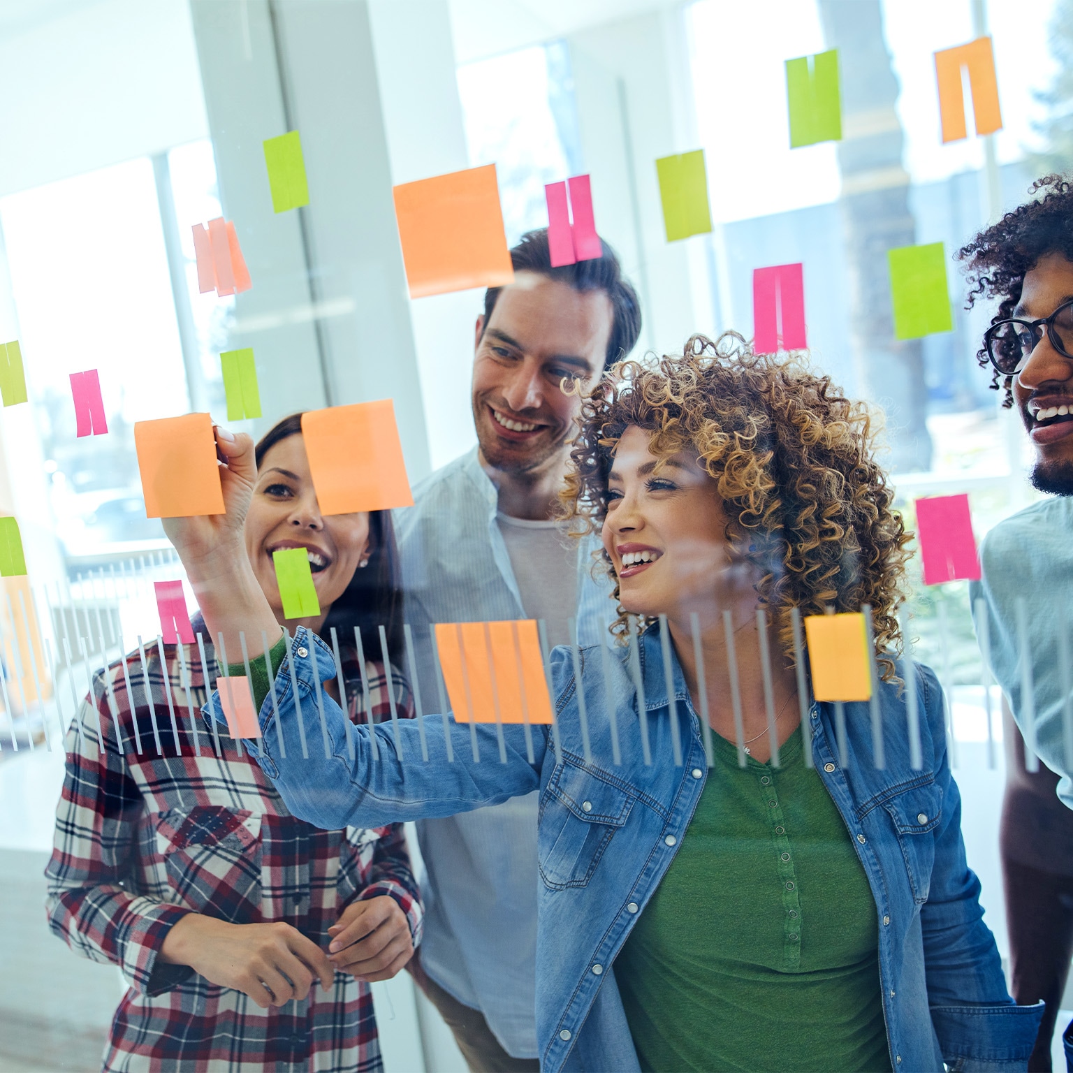  Image of a diverse team in an office brainstorming in front of a glass wall.