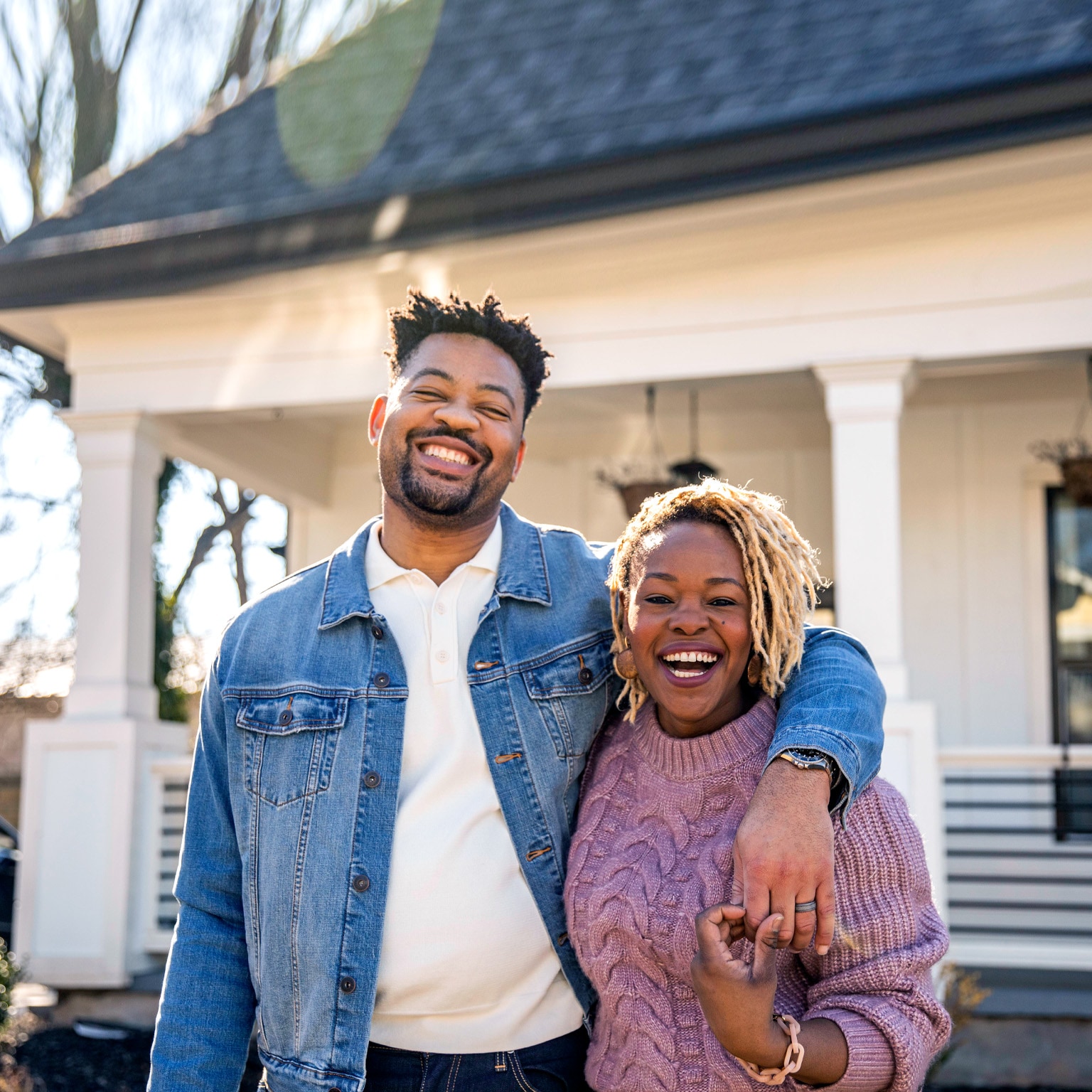 Portrait of husband and wife embracing in front of home