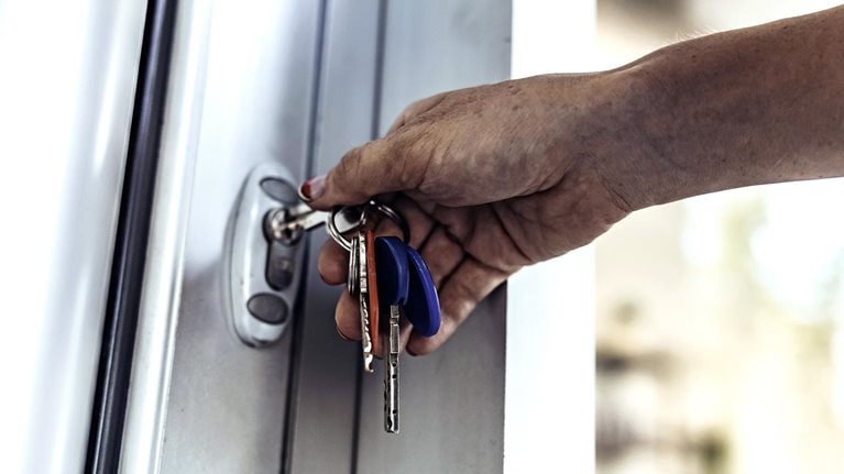 An close up image of a person's hand unlocking a door with a key.