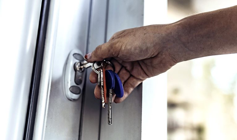 An close up image of a person's hand unlocking a door with a key.