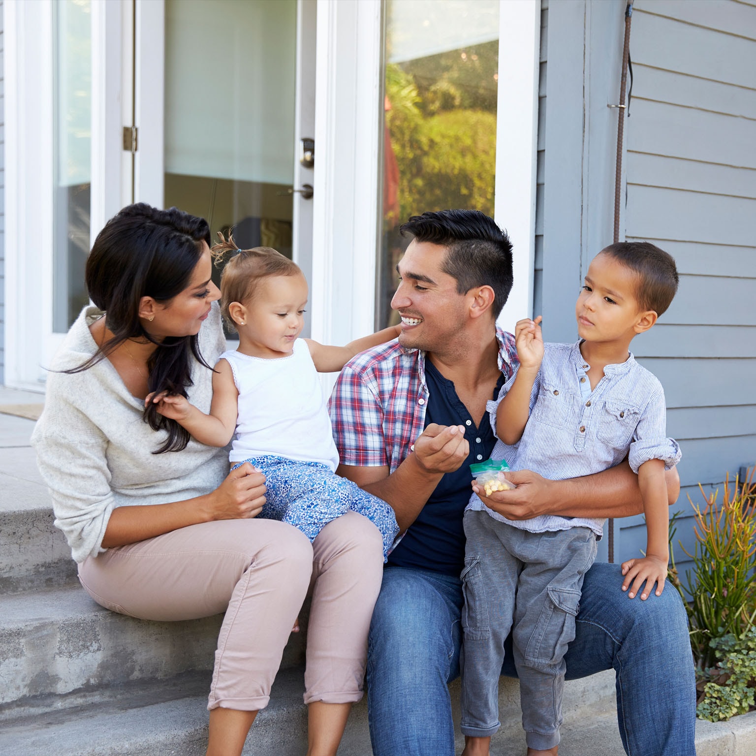 Father giving children candy on steps outside house