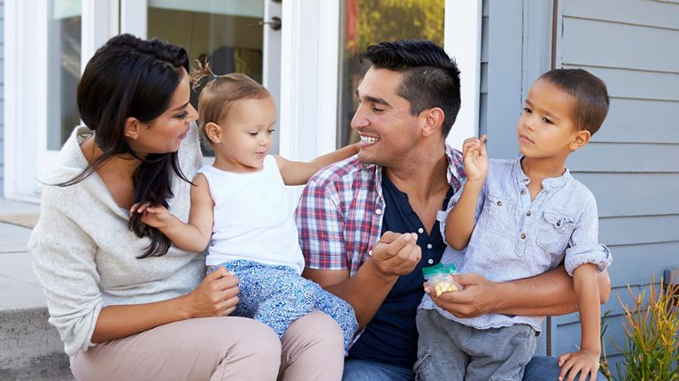 Father giving children candy on steps outside house