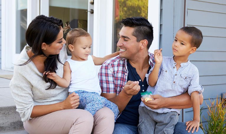 Father giving children candy on steps outside house