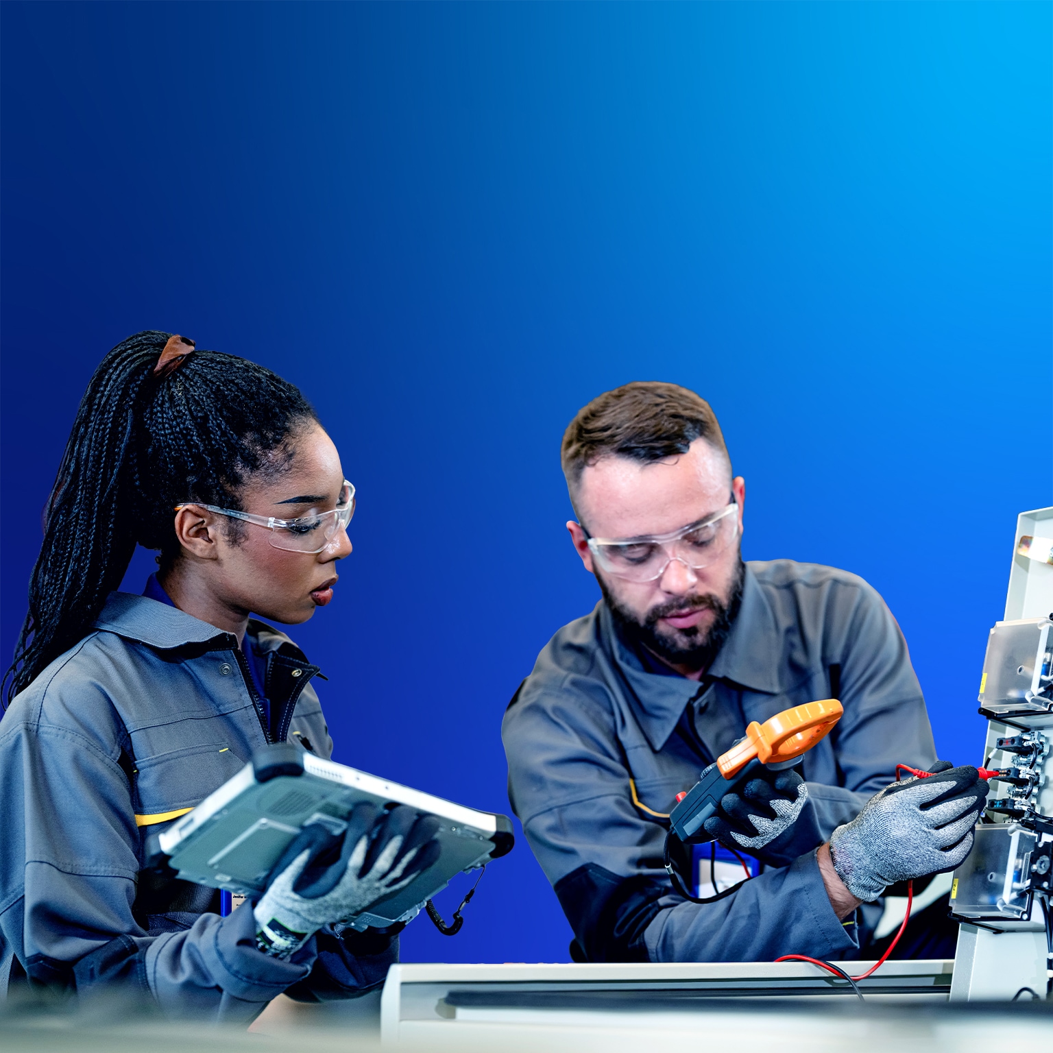 Young man and woman in work coveralls and safety gear have a discussion in a warehouse.