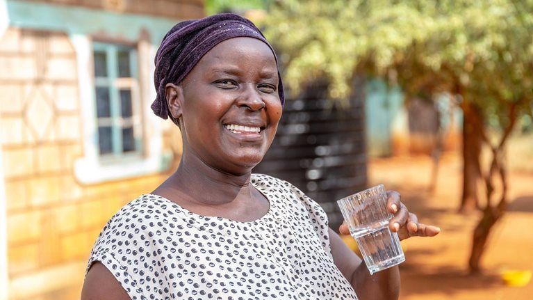 Woman smiling and holding a glass of water