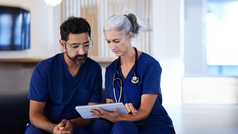 Two doctors working together, looking at digital tablet - stock photo