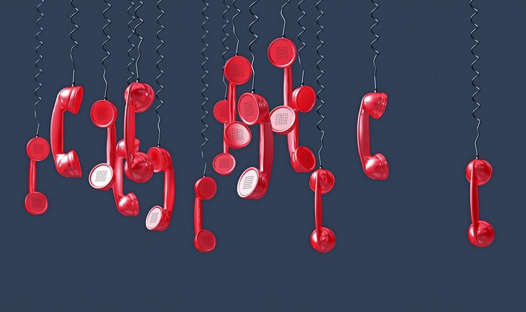 Image of numerous red phones hanging upside down by their cords.