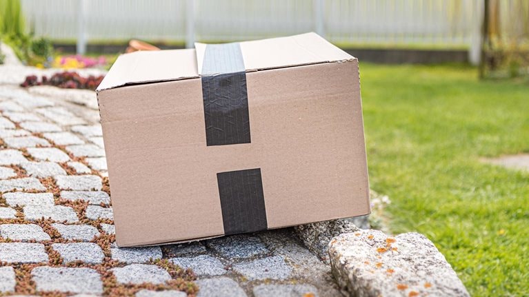 Parcel from a postal delivery is left in the garden because the recipient is not at home. - stock photo