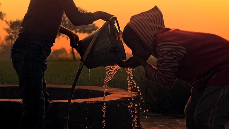Children drinking water on water well