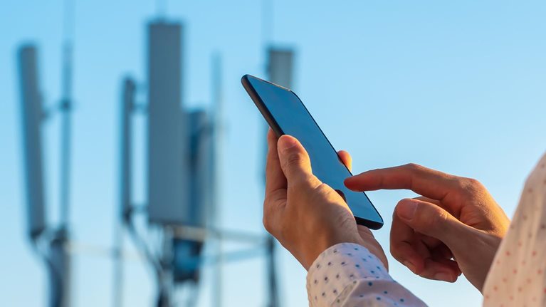 5G communications tower with man using mobile phone - stock photo