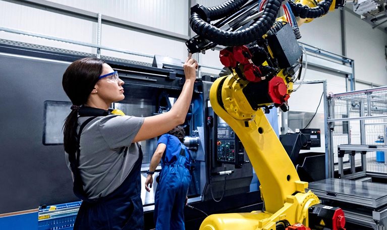 Maintenance engineer working in a factory using robotic arm